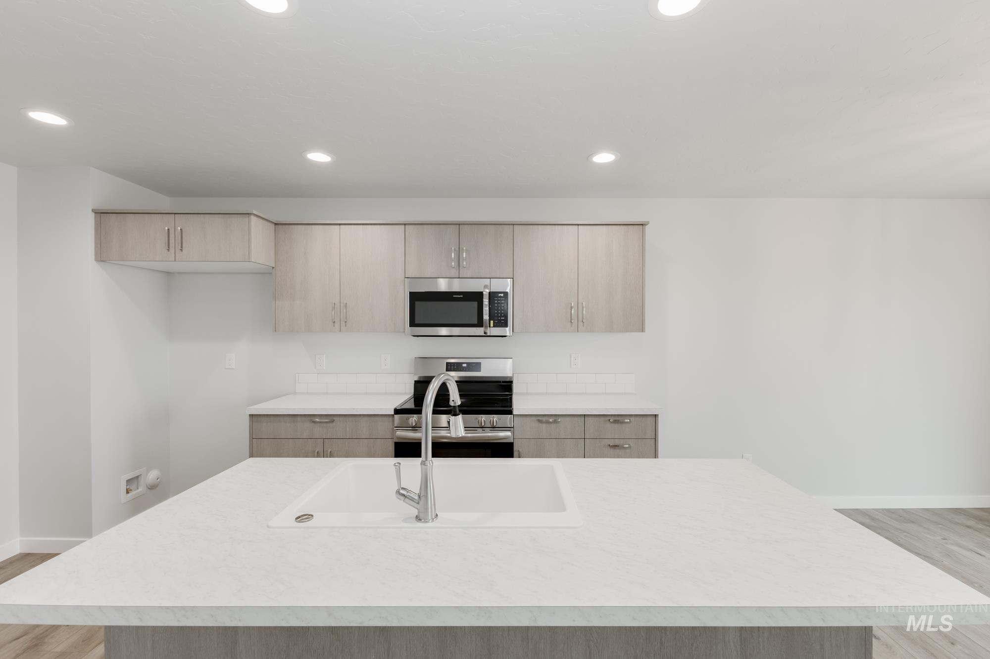 10873 Rutland Street Caldwell, ID 83605 - Photo 3 of 19 Kitchen featuring light wood-style flooring, light brown cabinetry, stainless steel appliances, light countertops, and recessed lighting