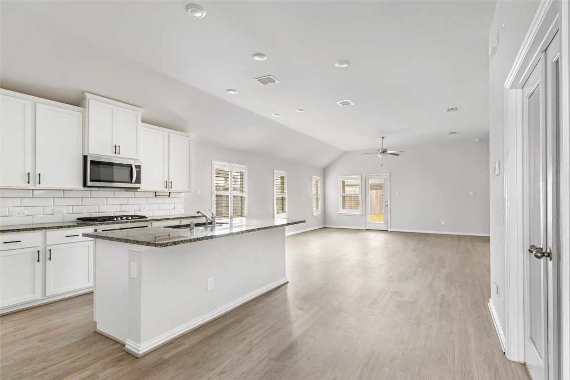 20811 Magical Merlin Way Tomball, TX 77375 - Photo 7 of 31 a kitchen with stainless steel appliances a stove top oven a sink a refrigerator white cabinets and wooden floor