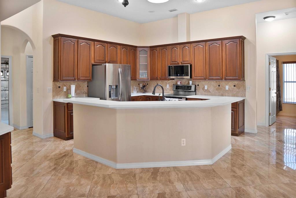 215 Strathmore Circle Kissimmee, FL 34744 - Photo 10 of 24 a kitchen with kitchen island granite countertop wooden cabinets a refrigerator and a sink