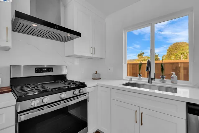 a kitchen with granite countertop a sink cabinets and stainless steel appliances