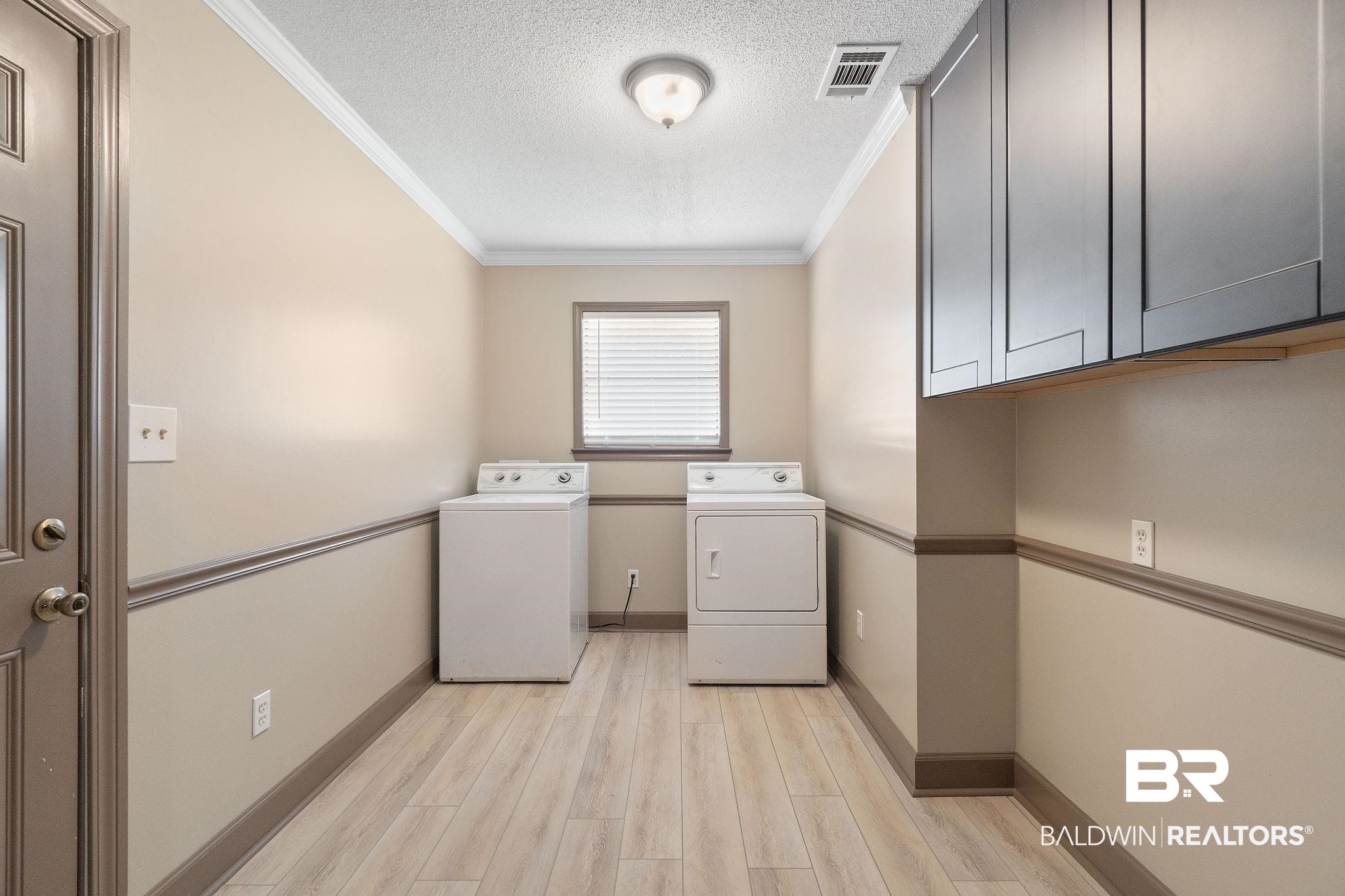 27300 C R Watson Road Robertsdale, AL 36567 - Photo 11 of 35 Washroom featuring ornamental molding, a textured ceiling, cabinets, independent washer and dryer, and light hardwood / wood-style floors