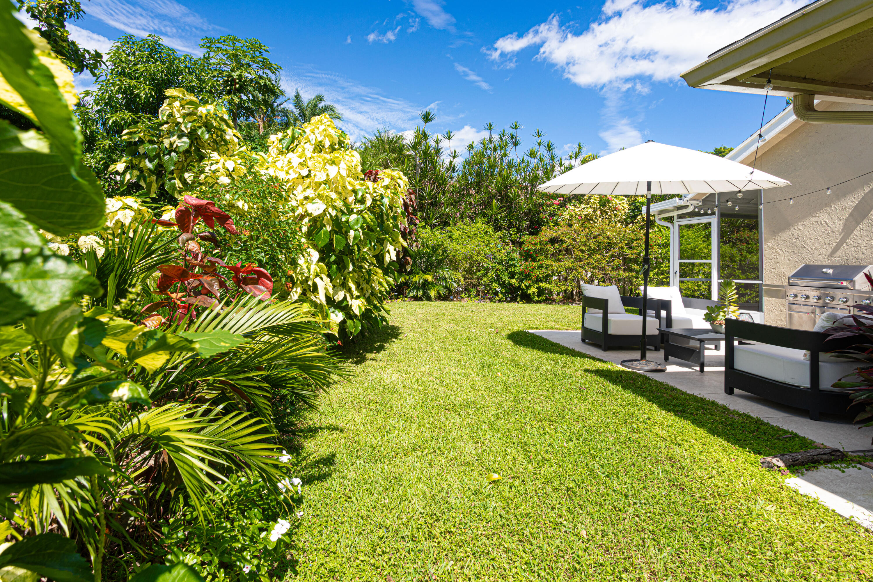 2477 Par Circle Delray Beach, FL 33445 - Photo 31 of 34 a backyard of a house with table and chairs under an umbrella