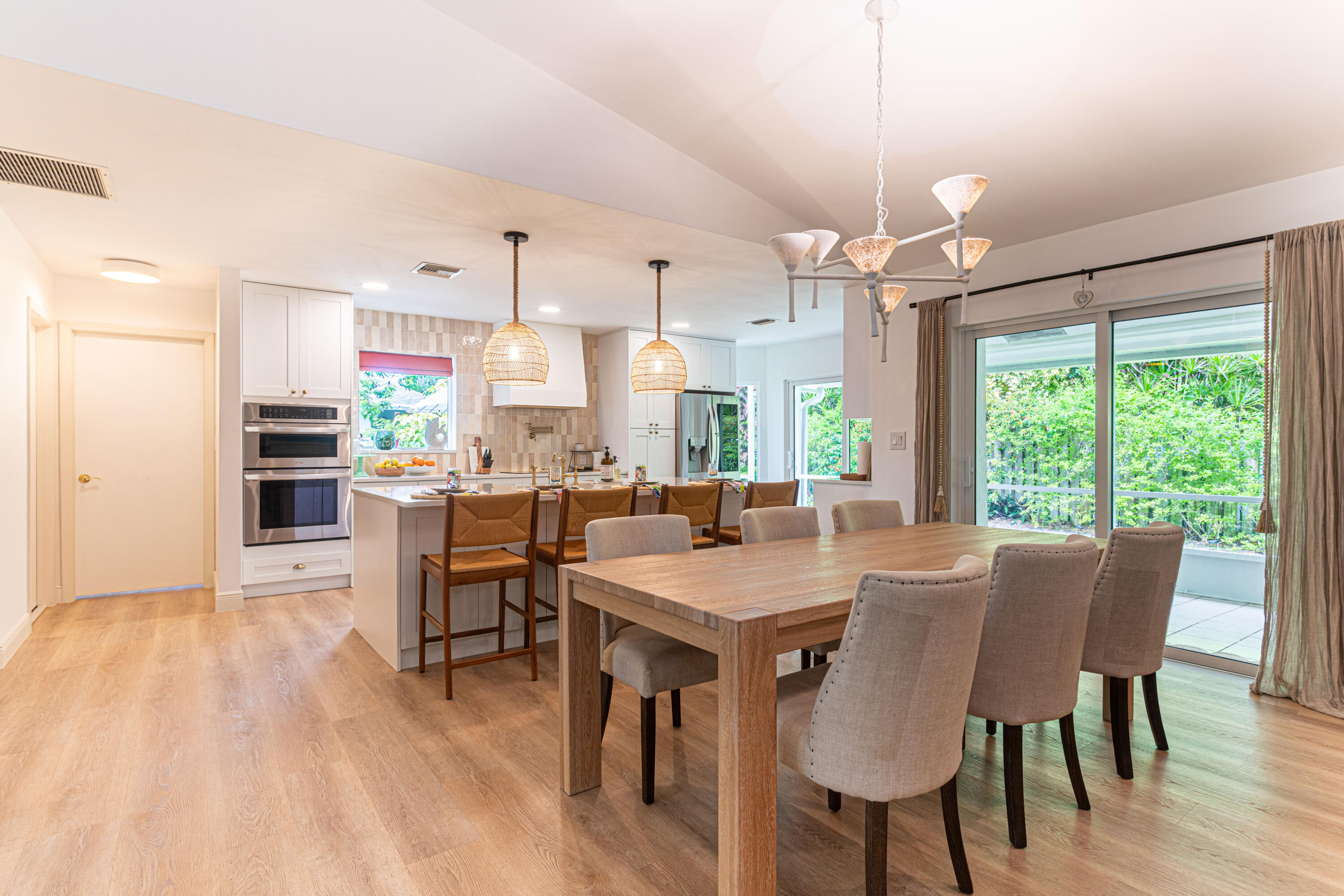 2477 Par Circle Delray Beach, FL 33445 - Photo 8 of 34 a view of a dining room and livingroom with furniture wooden floor a rug a flat screen tv a painting and a chandelier