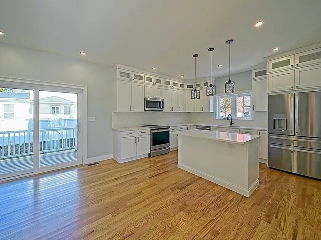 a kitchen with kitchen island white cabinets and stainless steel appliances