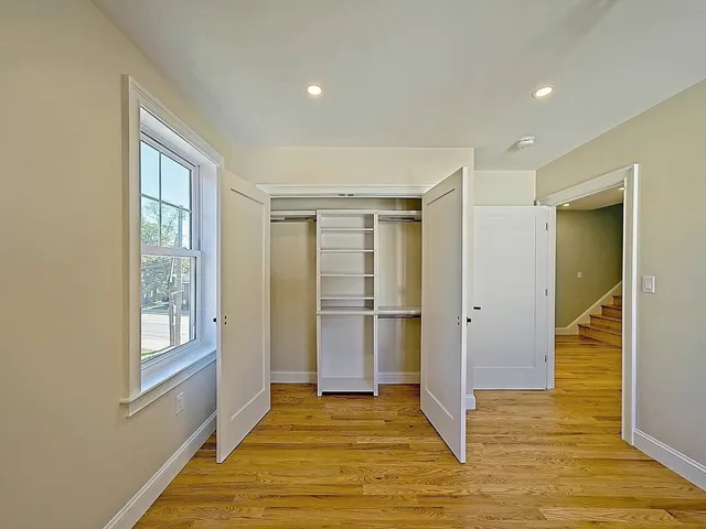 a view of an empty room with window and wooden floor