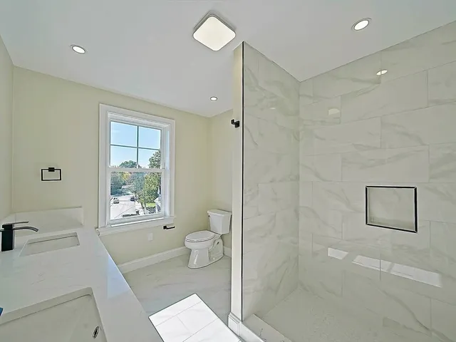 a spacious bathroom with double sink a large mirror and shower