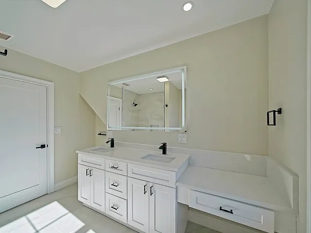 a spacious bathroom with double sink a large mirror and shower