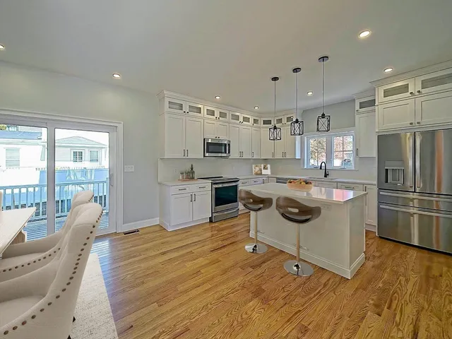 a kitchen with stainless steel appliances a stove a refrigerator a kitchen island a stove and white cabinets