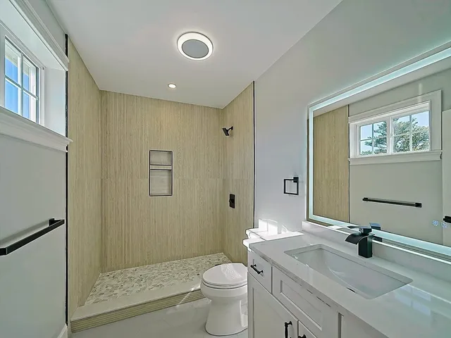 a bathroom with a granite countertop sink toilet and shower