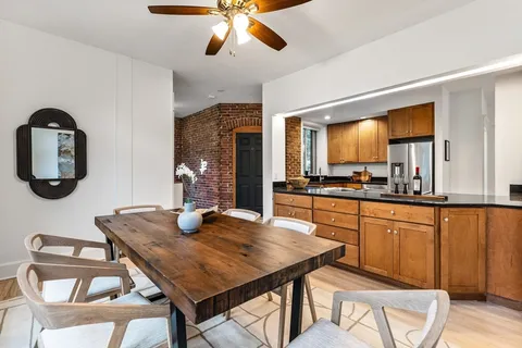 a kitchen with stainless steel appliances granite countertop a kitchen island a stove a dining table and chairs with wooden floor