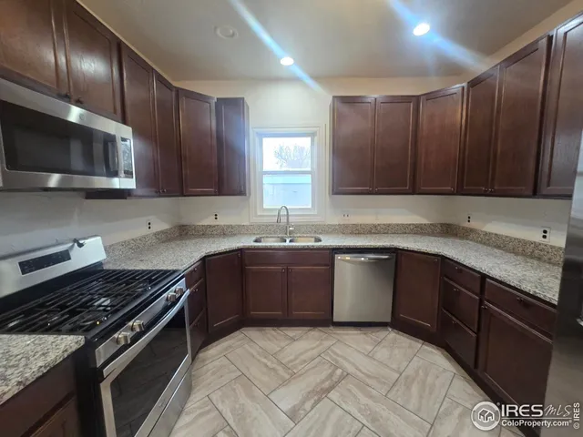 a kitchen with stainless steel appliances granite countertop wooden cabinets a stove top oven a sink and dishwasher
