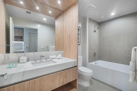 a bathroom with a double vanity sink toilet mirror and bathtub