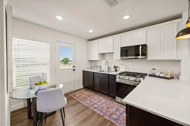 a kitchen with a stove a sink a microwave a dining table and chairs