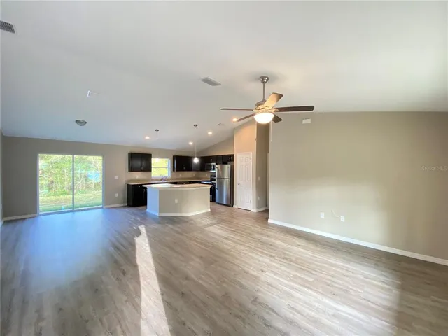 a living room with hard wood floors and kitchen