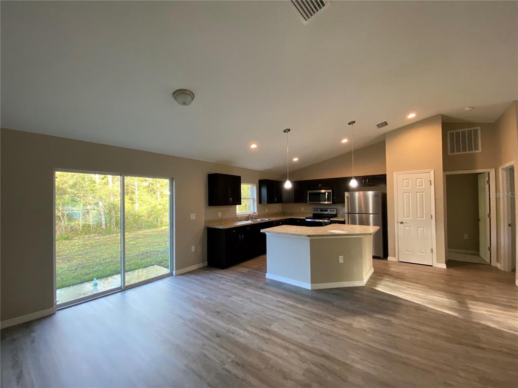 5366 Southwest 197th Terrace Dunnellon, FL 34431 - Photo 7 of 29 a large kitchen with kitchen island a sink wooden floor and a large window