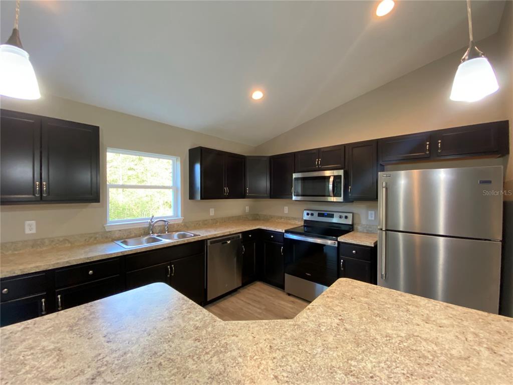 5366 Southwest 197th Terrace Dunnellon, FL 34431 - Photo 10 of 29 a kitchen with stainless steel appliances kitchen island granite countertop a sink stove and refrigerator