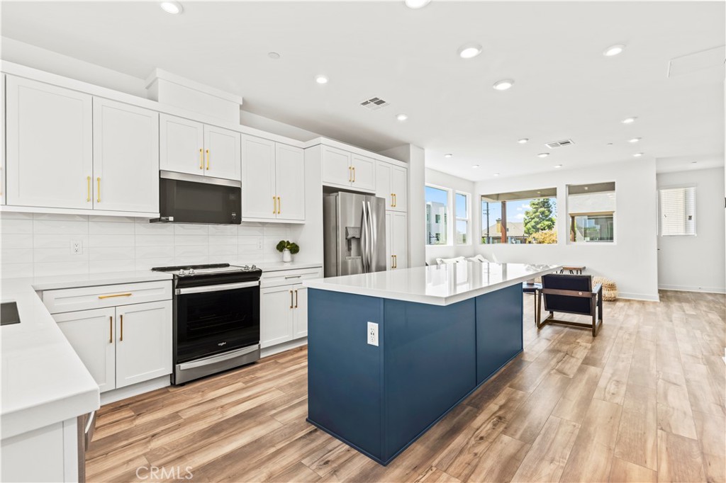 609 South Lyon Street Santa Ana, CA 92705 - Photo 7 of 52 a kitchen with stainless steel appliances granite countertop a stove top oven a sink dishwasher and a refrigerator with wooden floor