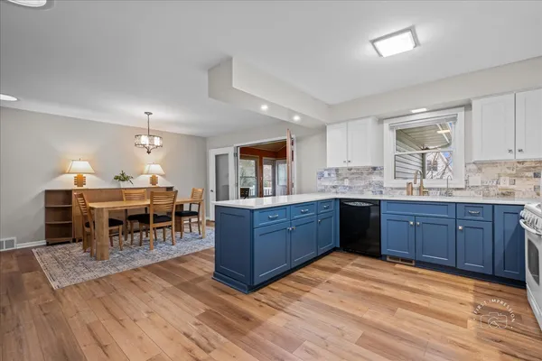 a kitchen with stainless steel appliances granite countertop a stove a sink dishwasher a dining table and chairs with wooden floor