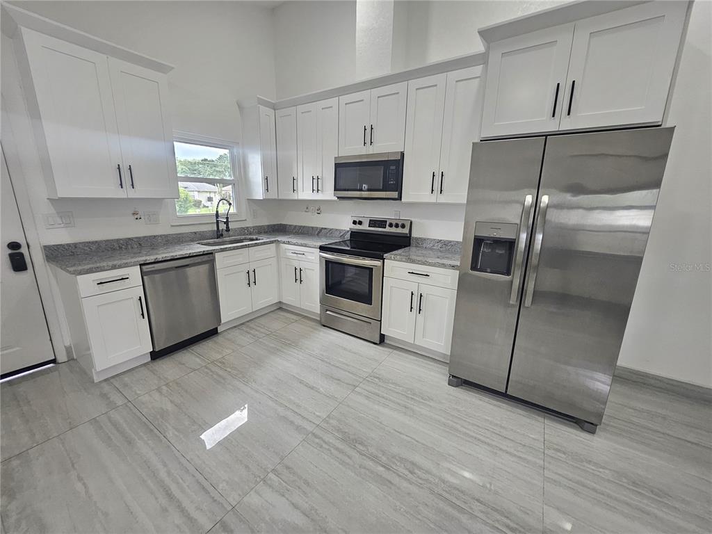 5802 Mohr Loop, Unit 5802 5804 5806 5808 Tampa, FL 33615 - Photo 18 of 40 a kitchen with granite countertop stainless steel appliances and wooden cabinets