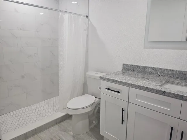 a bathroom with a granite countertop sink toilet and a mirror