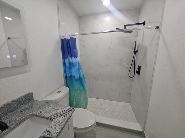 a bathroom with a granite countertop bathtub shower sink and toilet