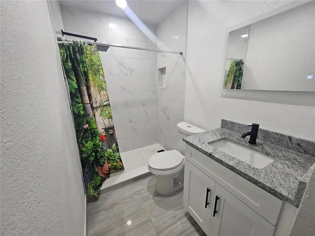 a bathroom with a granite countertop sink toilet and shower