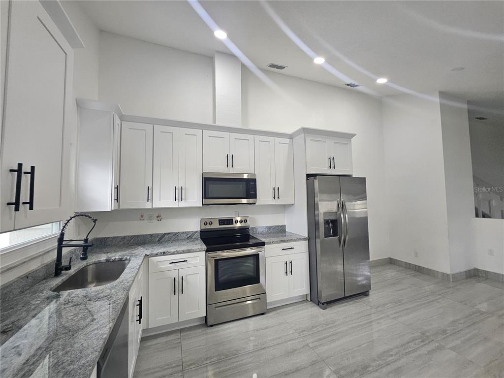 5802 Mohr Loop, Unit 5802 5804 5806 5808 Tampa, FL 33615 - Photo 35 of 40 a kitchen with stainless steel appliances granite countertop a refrigerator stove a sink and white cabinets