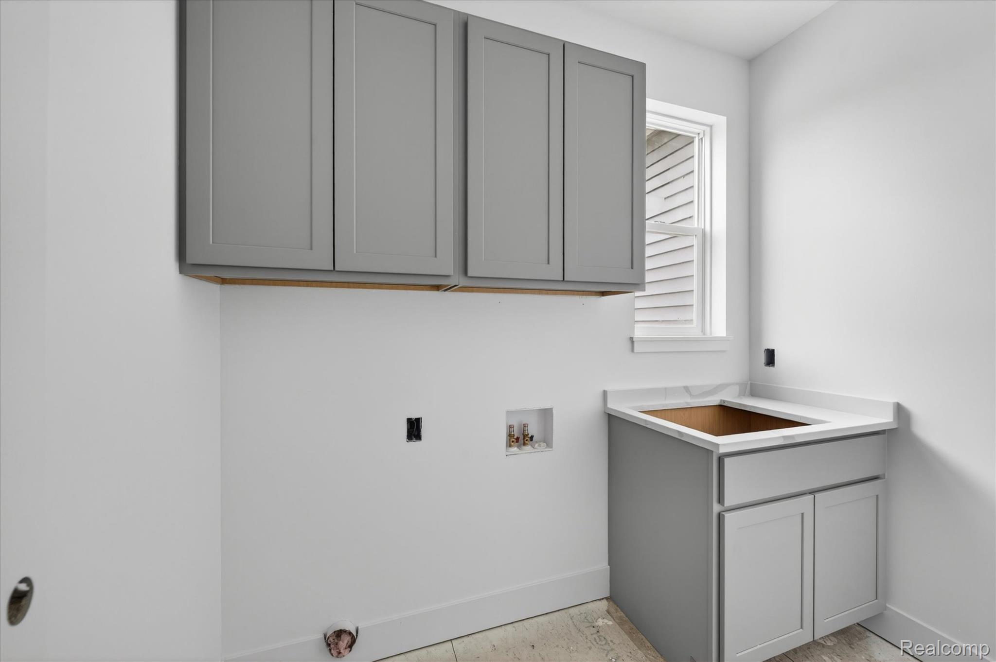3297 Oak Grove Road Howell, MI 48855 - Photo 13 of 40 Functional laundry room with upper cabinetry, utility sink, and quartz countertop.