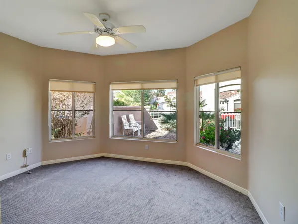 an empty room with windows and ceiling fan