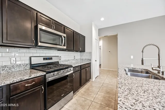 a kitchen with stainless steel appliances granite countertop a stove microwave and sink
