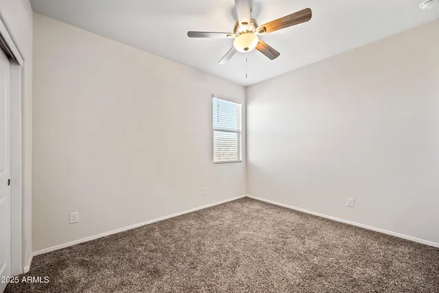 an empty room with a window and a ceiling fan