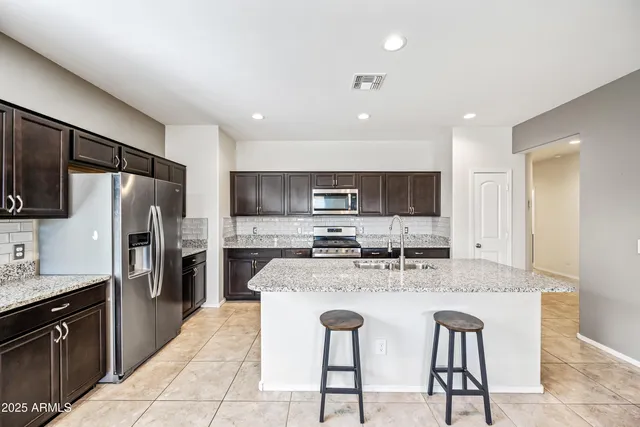 a large kitchen with kitchen island granite countertop a sink and stainless steel appliances