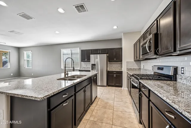 a kitchen with stainless steel appliances granite countertop a sink stove and refrigerator