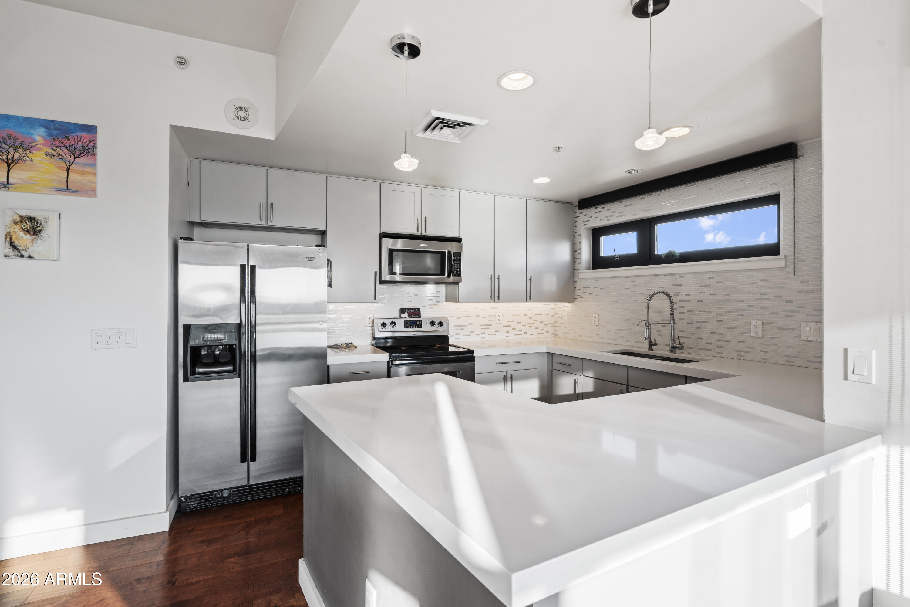 310 South 4th Street, Unit 601 Phoenix, AZ 85004 - Photo 6 of 29 a kitchen with stainless steel appliances granite countertop a refrigerator a sink a stove a oven a dining table and chairs with wooden floor