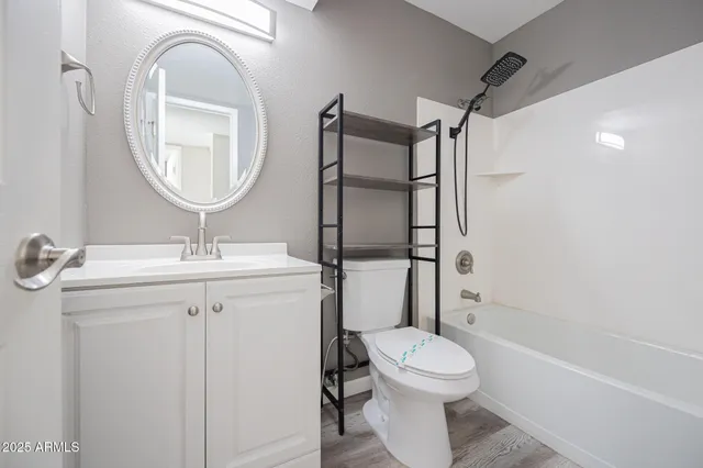 a bathroom with a toilet sink vanity granite and shower