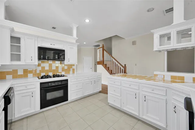 a kitchen with granite countertop white cabinets and stainless steel appliances