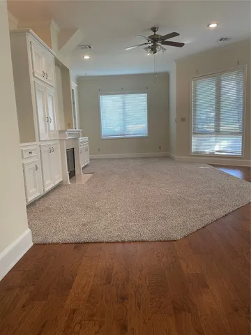 an empty room with chandelier fan and windows