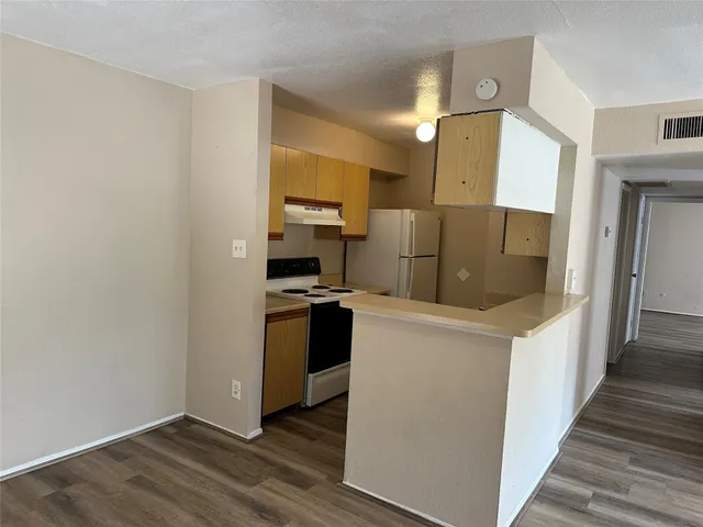 a kitchen with a refrigerator a stove top oven and wooden floor