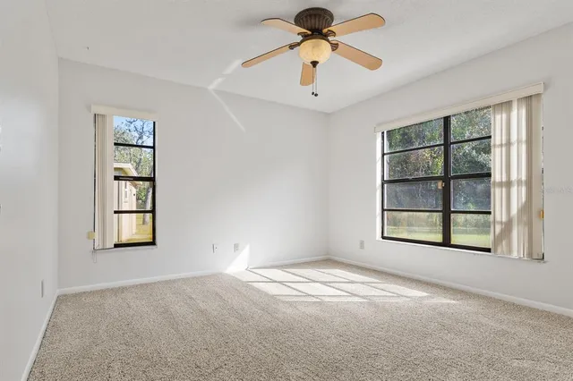 an empty room with windows and fan