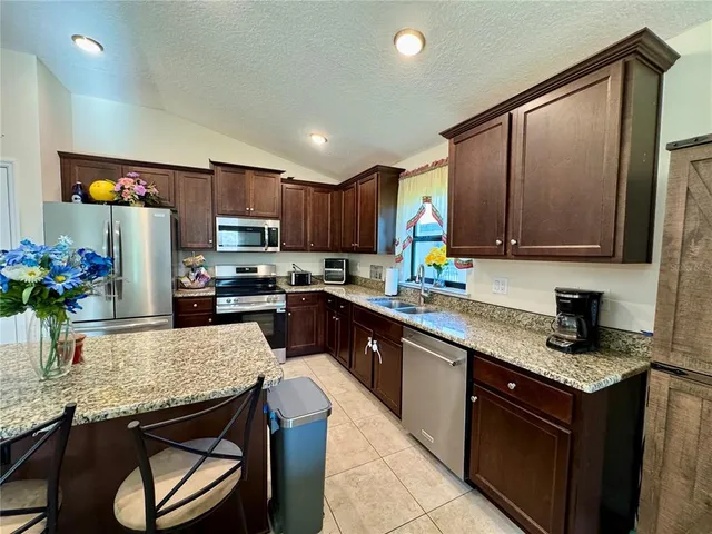 a large kitchen with a table chairs refrigerator and a sink