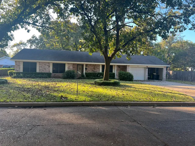 a view of house with a yard and large trees