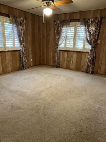 an empty room with windows and fan