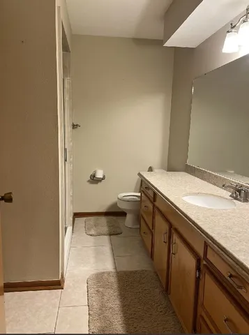 a bathroom with a granite countertop sink a toilet and shower