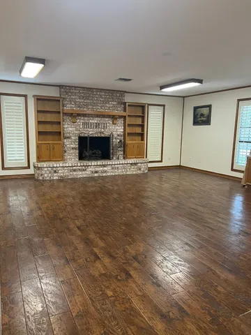 an empty room with wooden floor and a fireplace