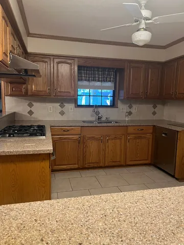 a kitchen with stainless steel appliances granite countertop a sink a stove top oven a counter space and cabinets