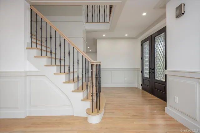 a view of an empty room with wooden floor and a kitchen