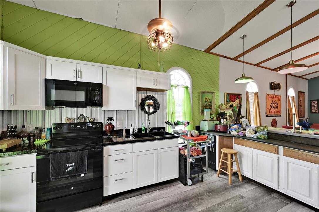 101 Conrad Road Fleetwood, PA 19522 - Photo 8 of 42 A well-equipped kitchen boasts ample white cabinetry and sleek black countertops, highlighted by wood-beamed ceilings.