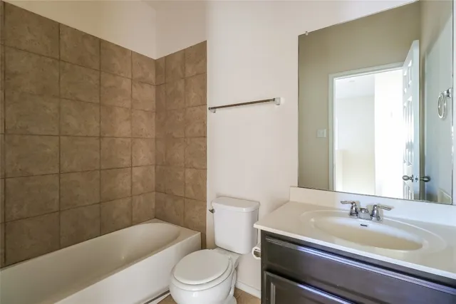 a bathroom with a granite countertop bathtub shower sink vanity and toilet