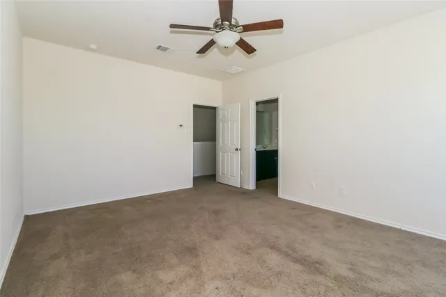 an empty room with closet and a ceiling fan