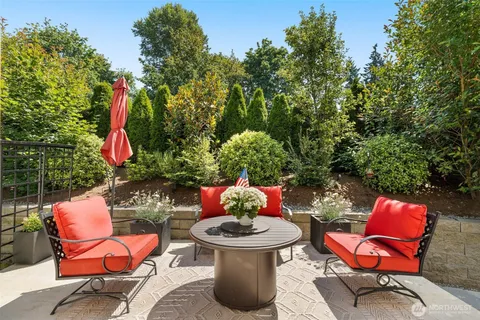 a backyard with table and chairs potted plants and a fire pit